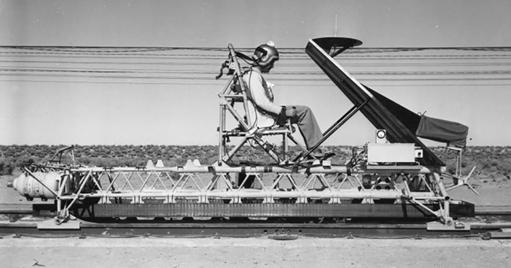 Human strapped into a chair atop a rocket sled on railroad tracks